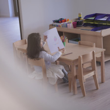 Enfant assis sur une chaise en bois avec une feuille à la main 