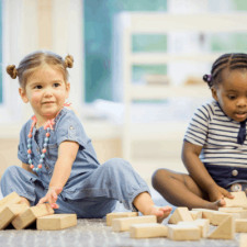 Enfants assis sur le sol jouant avec des objets en bois 